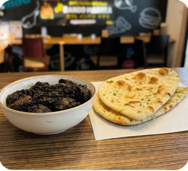 Beef kala bhuna in a bowl with two naan